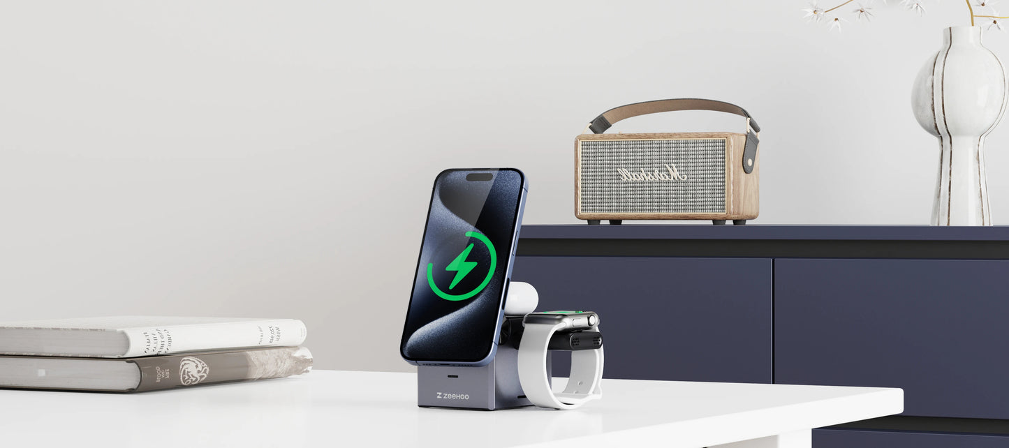 Phone on a stand with a charging cable, mug, and speaker on a table.